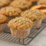 Peach muffins with streusel topping on a cooling rack.