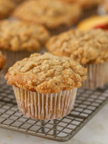 Peach muffins with streusel topping on a cooling rack.