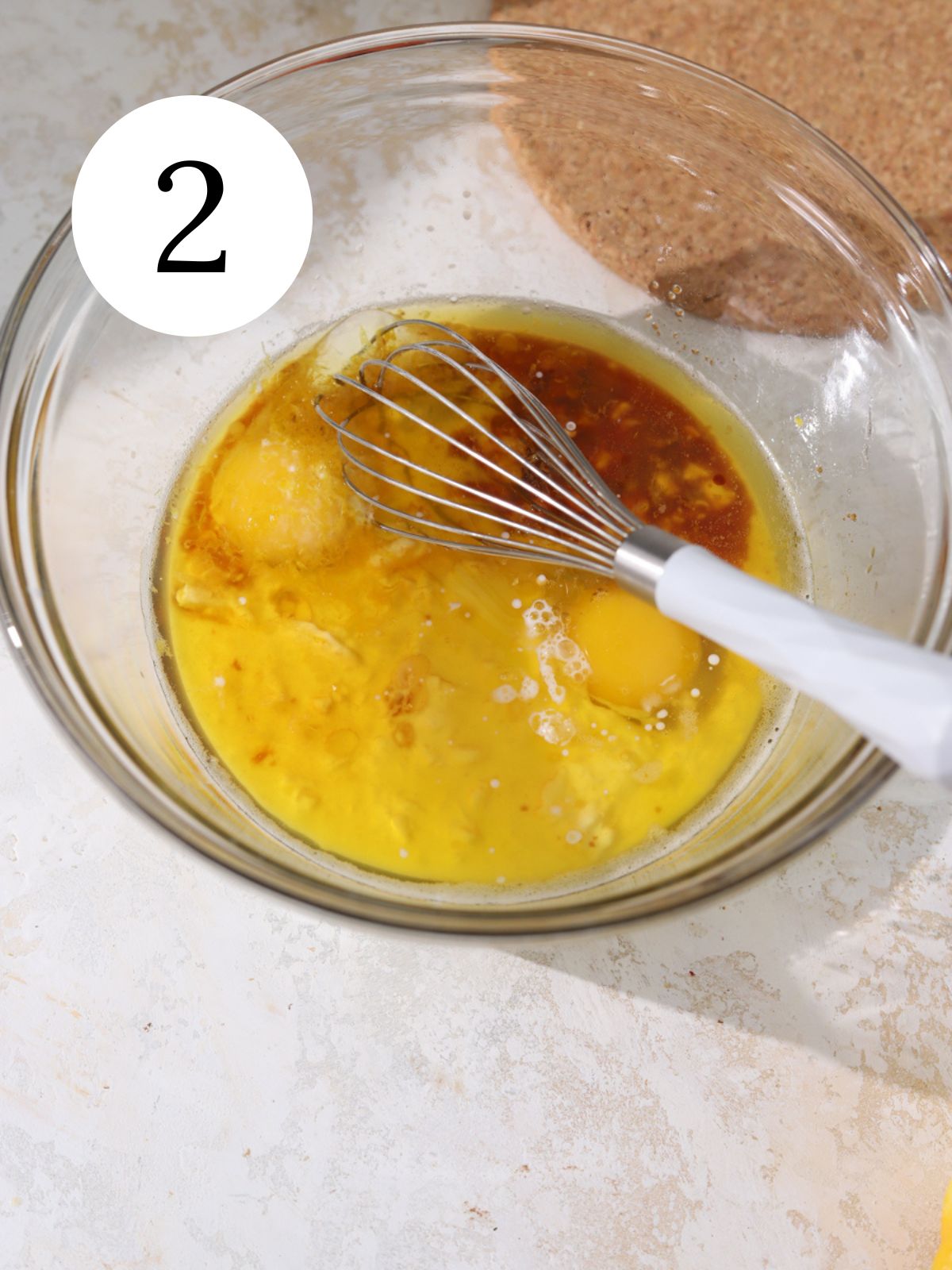 Eggs, melted butter and other wet ingredients in a bowl with a whisk. 