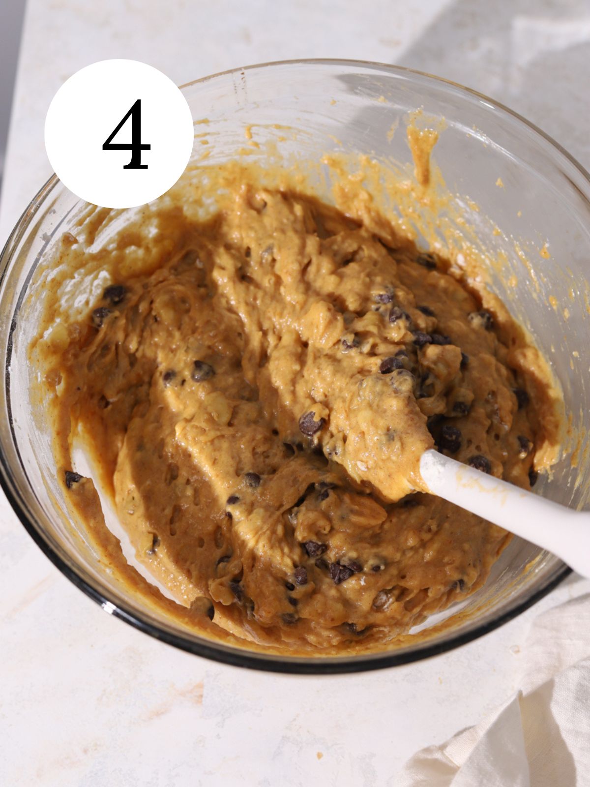 Pumpkin bread batter with chocolate chips in a bowl with a spatula.