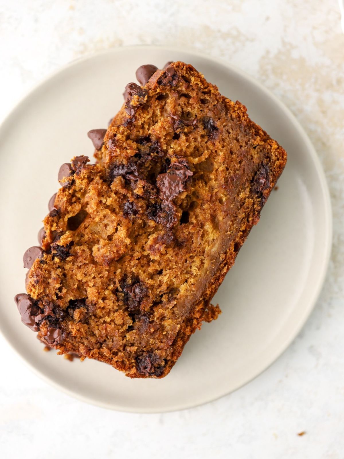 A slice of pumpkin banana bread with chocolate on a plate.