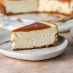 A piece of brown butter cheesecake topped with caramel sauce.