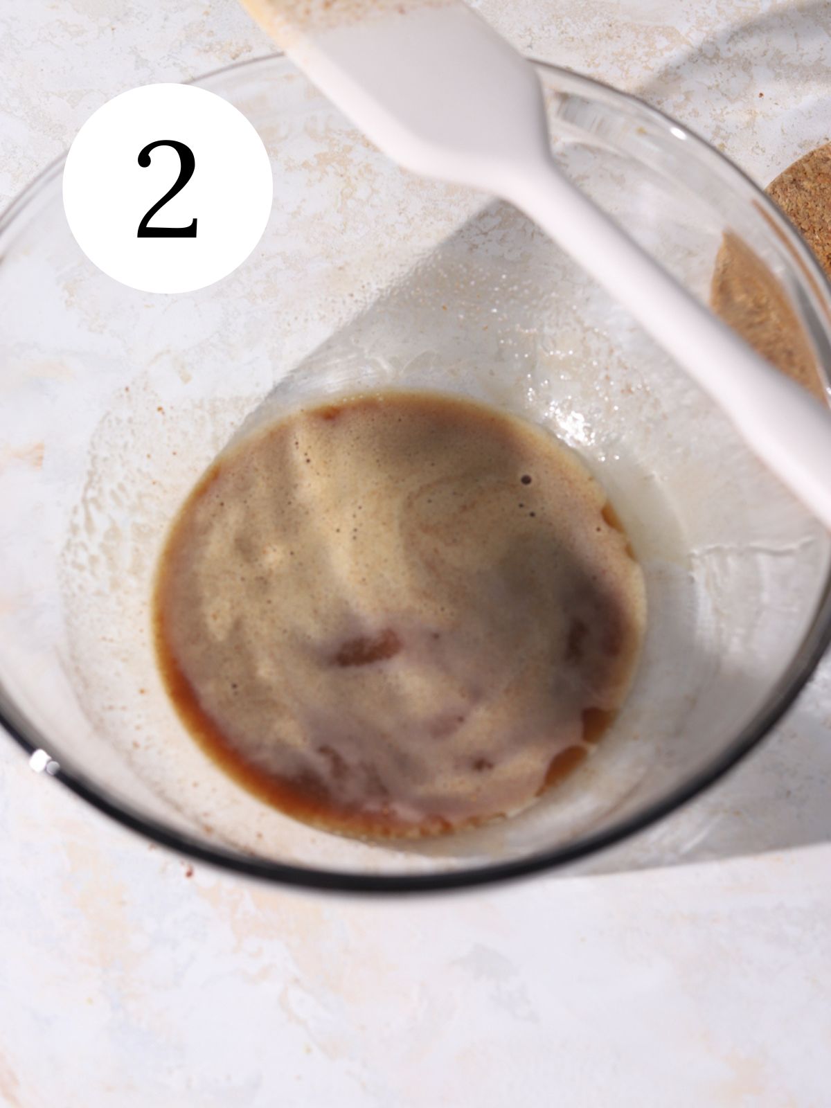 Brown butter with spices in a glass bowl with a spatula on the edge.