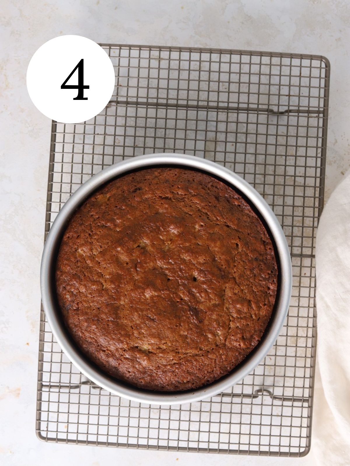 A banana cake in a pan set on a baking rack.