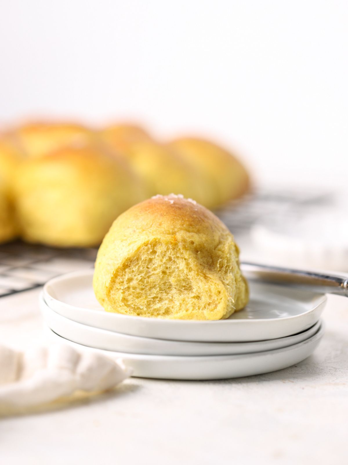A golden squash roll on a stack of white plates.