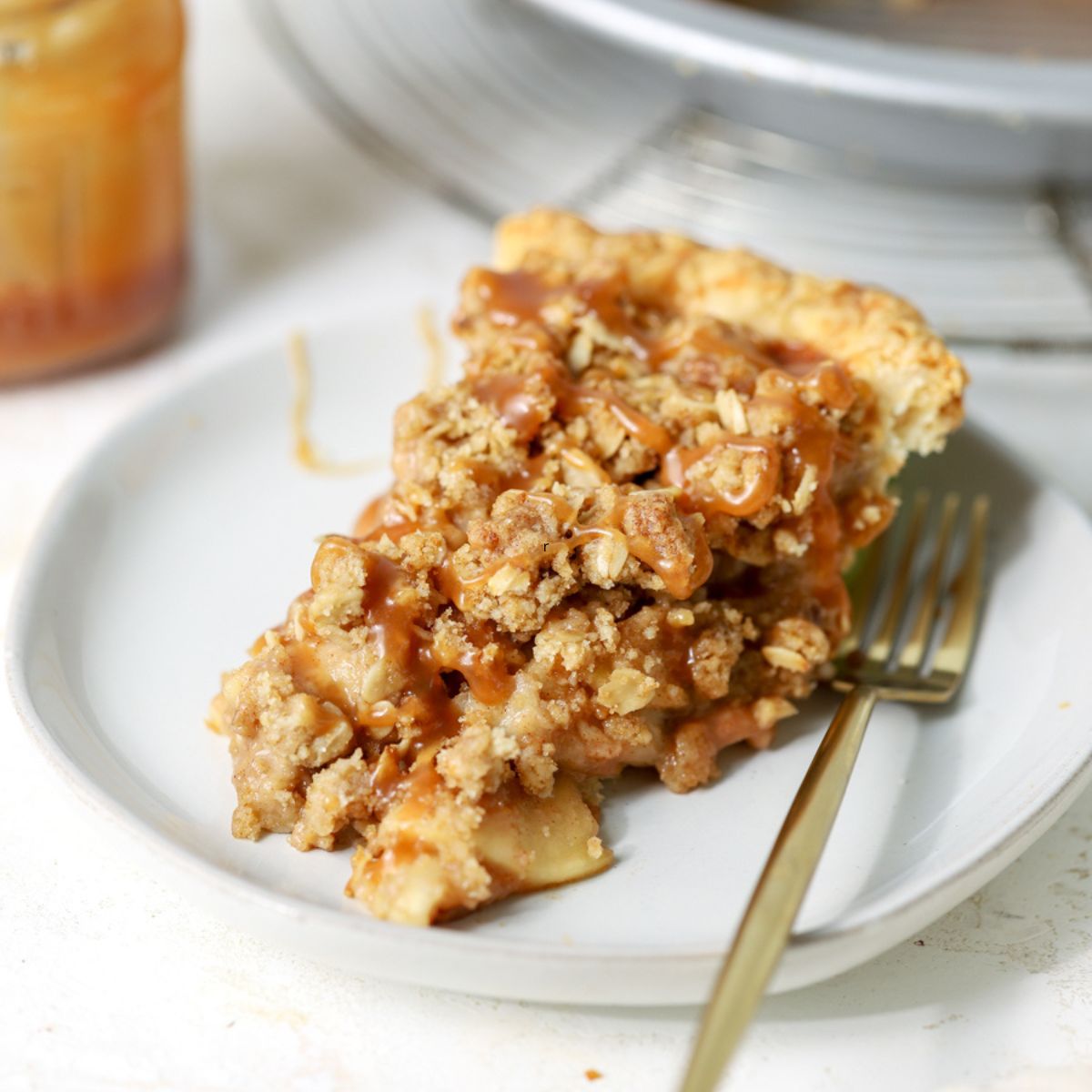A slice of apple crumble pie topped with caramel sauce.