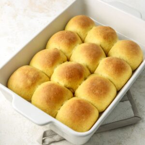 A batch of golden squash rolls in a rectangular pan.