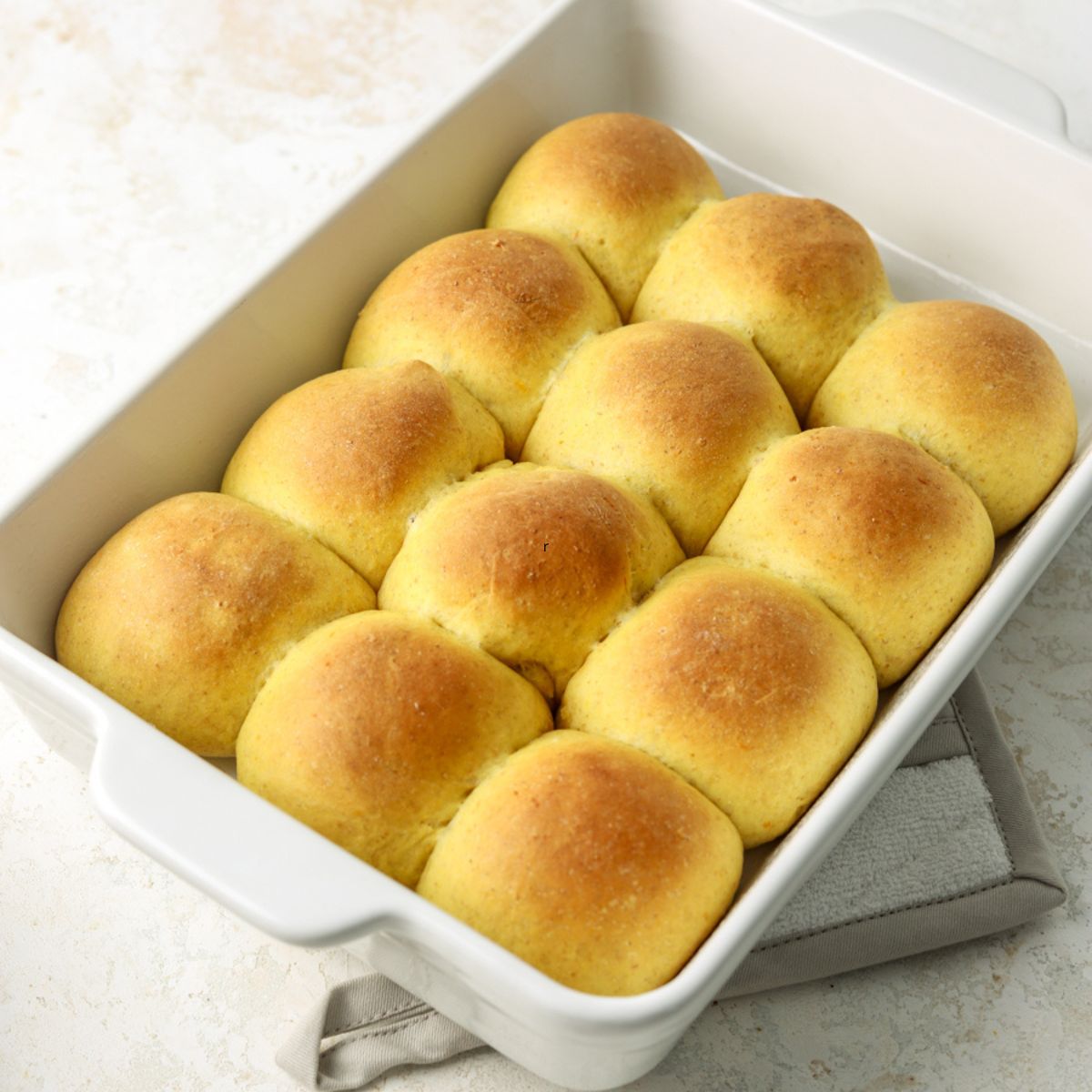 A batch of golden squash rolls in a rectangular pan.