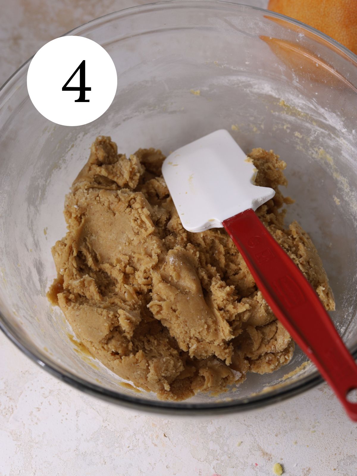 Cookie dough in a glass bowl with a spatula.