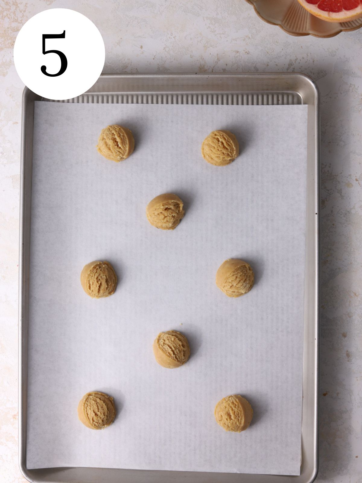 Cookie dough balls on a baking sheet lined with parchment paper.
