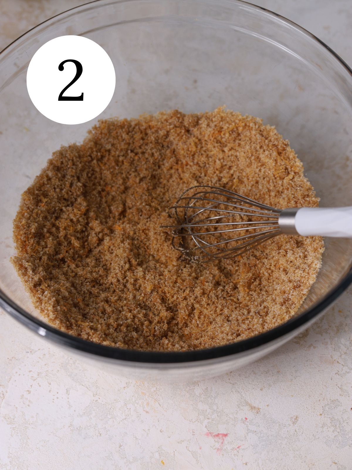 A glass bowl with brown sugar and granulated sugar whisked together.