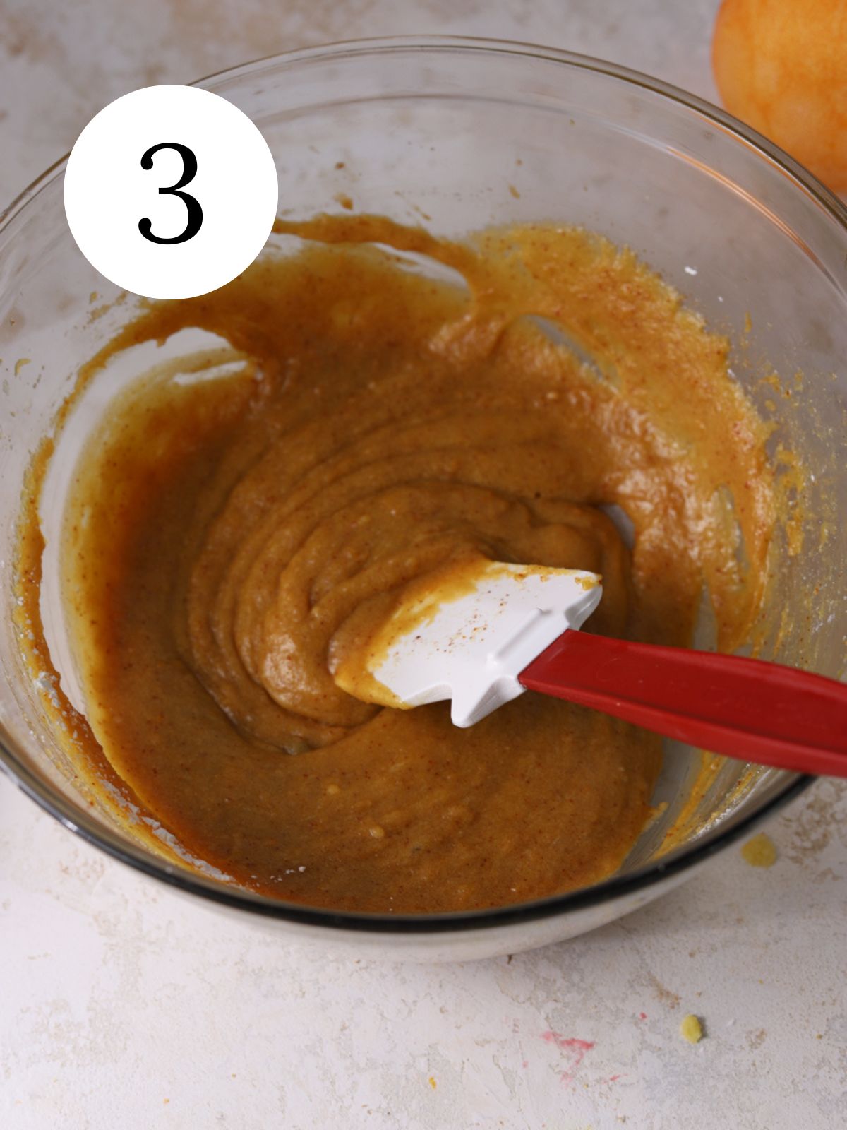 Wet ingredients stirred together in a bowl with a spatula.