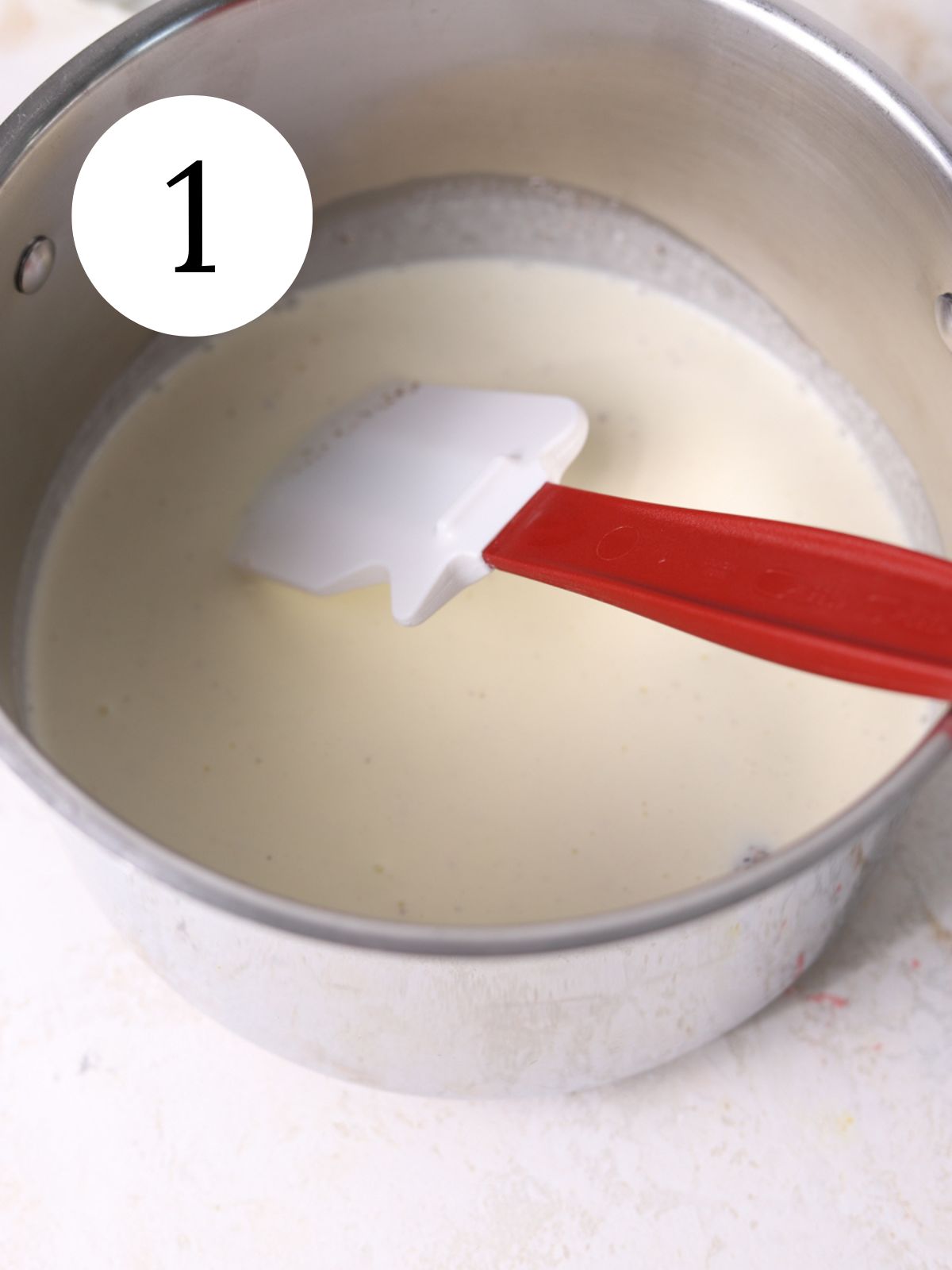 Warmed heavy cream in a saucepan with a spatula.