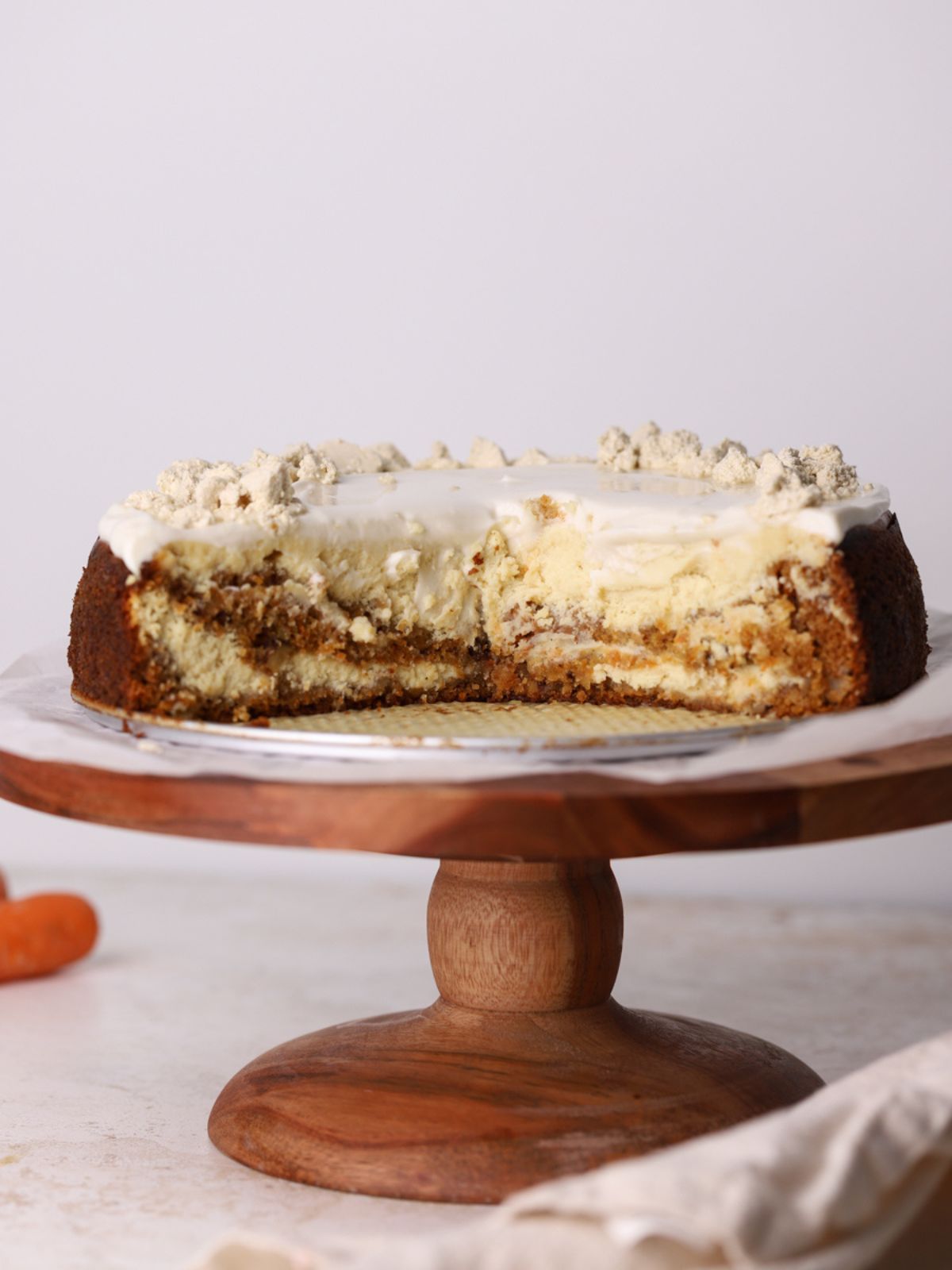 A carrot cake cheesecake on a cake stand.