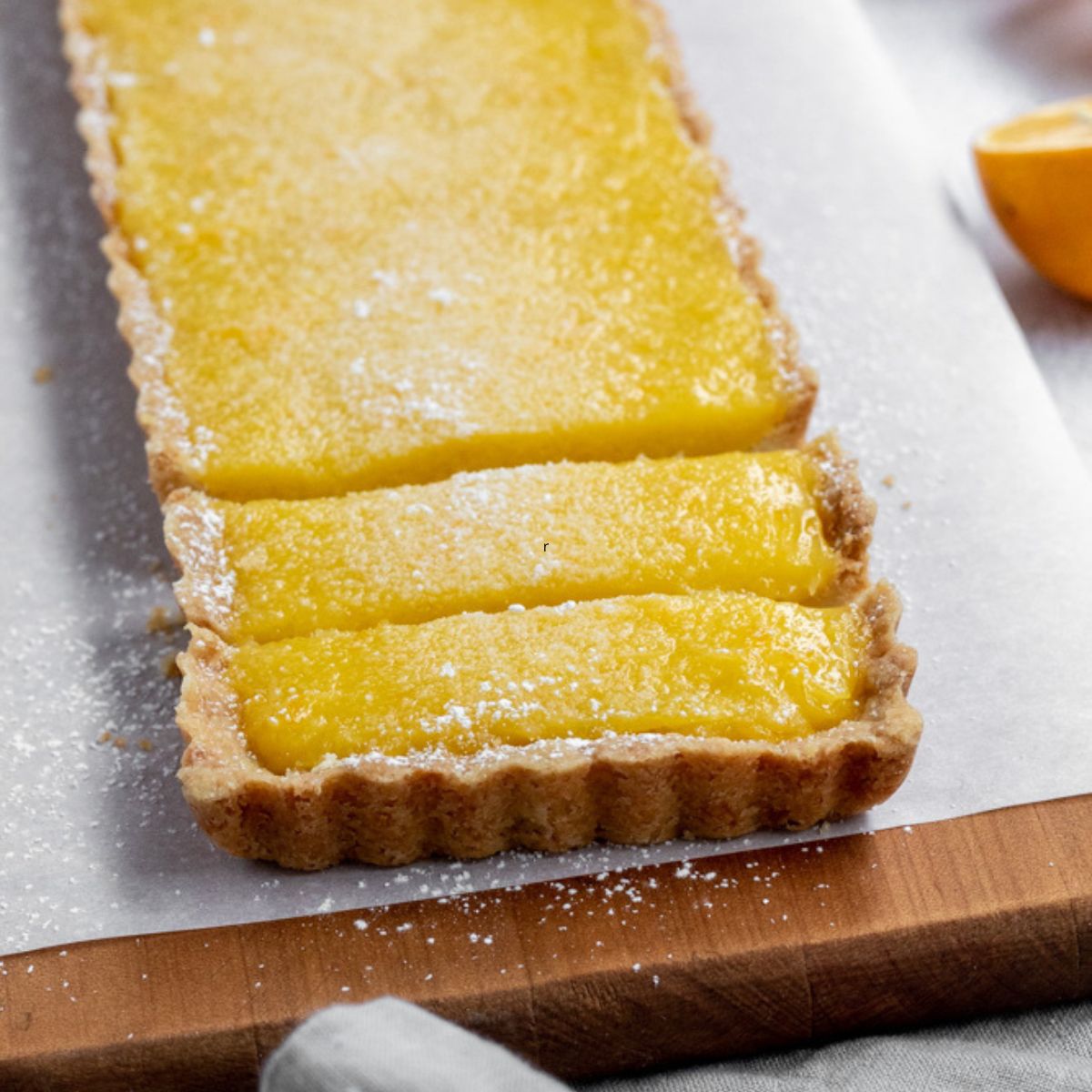 A rectangular shaped lemon tart sliced.