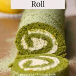 A matcha roll cake with whipped cream filling on parchment paper.