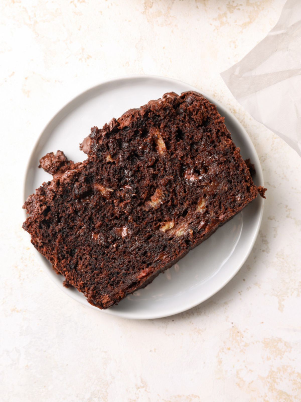 A slice of chocolate banana bread on a white plate.