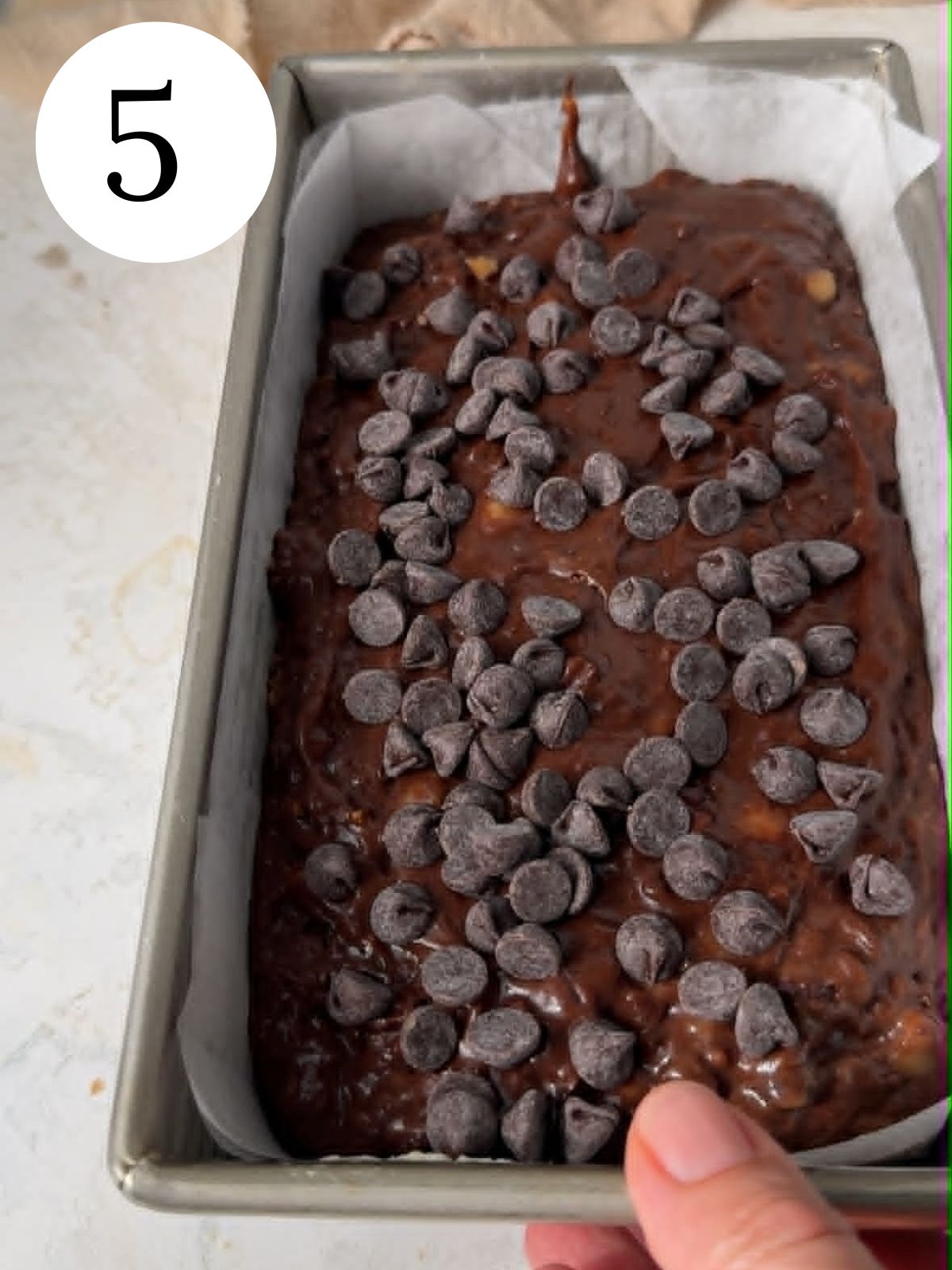 Chocolate bread in a loaf pan with chocolate chips on top.