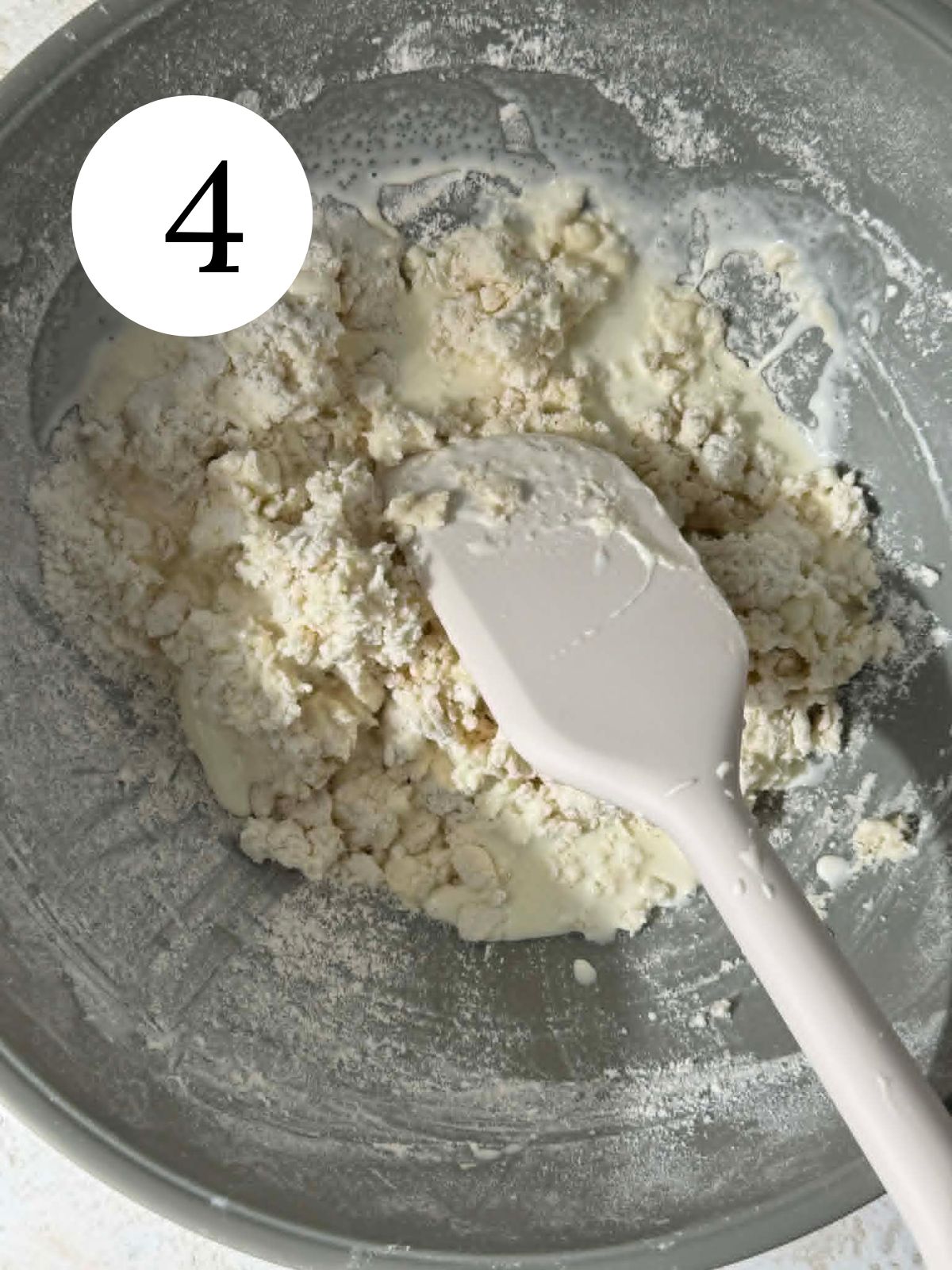 Cream added to a mixture of butter and flour in a bowl with a spatula.