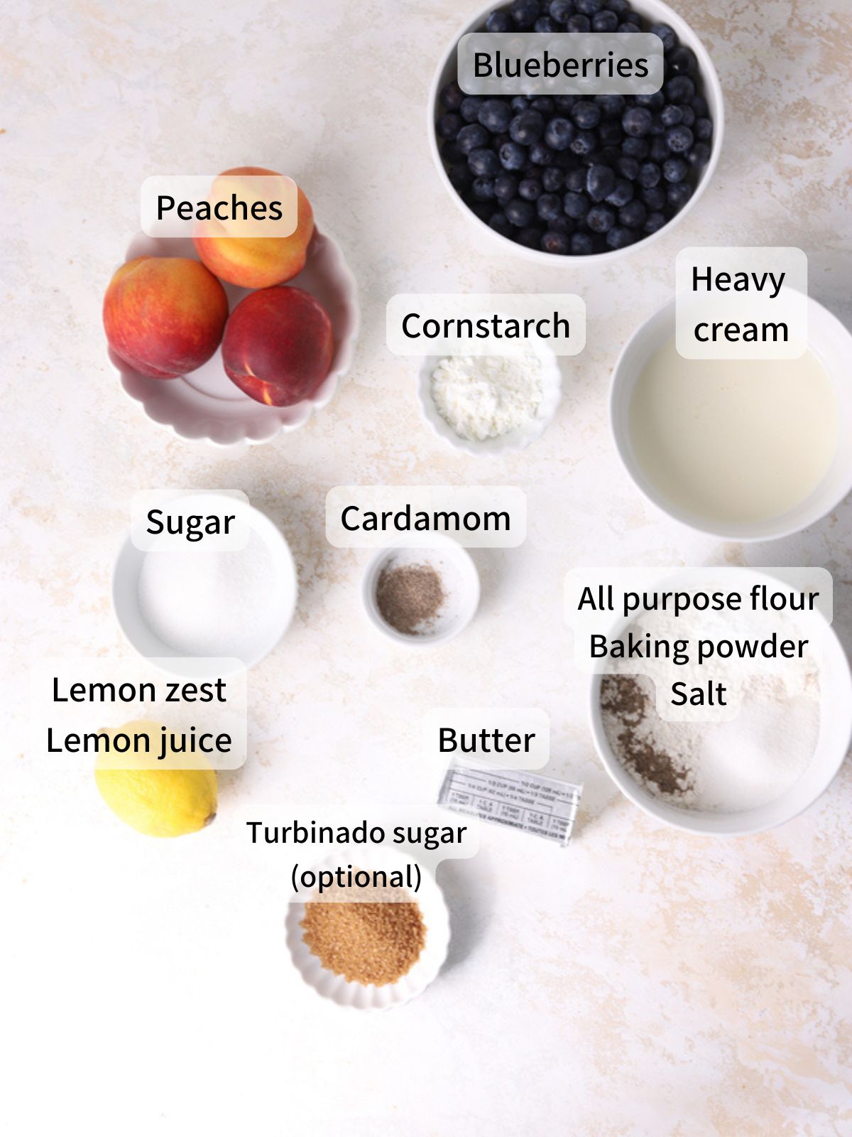 Labeled ingredients needed to make peach blueberry cobbler laid out on a table.