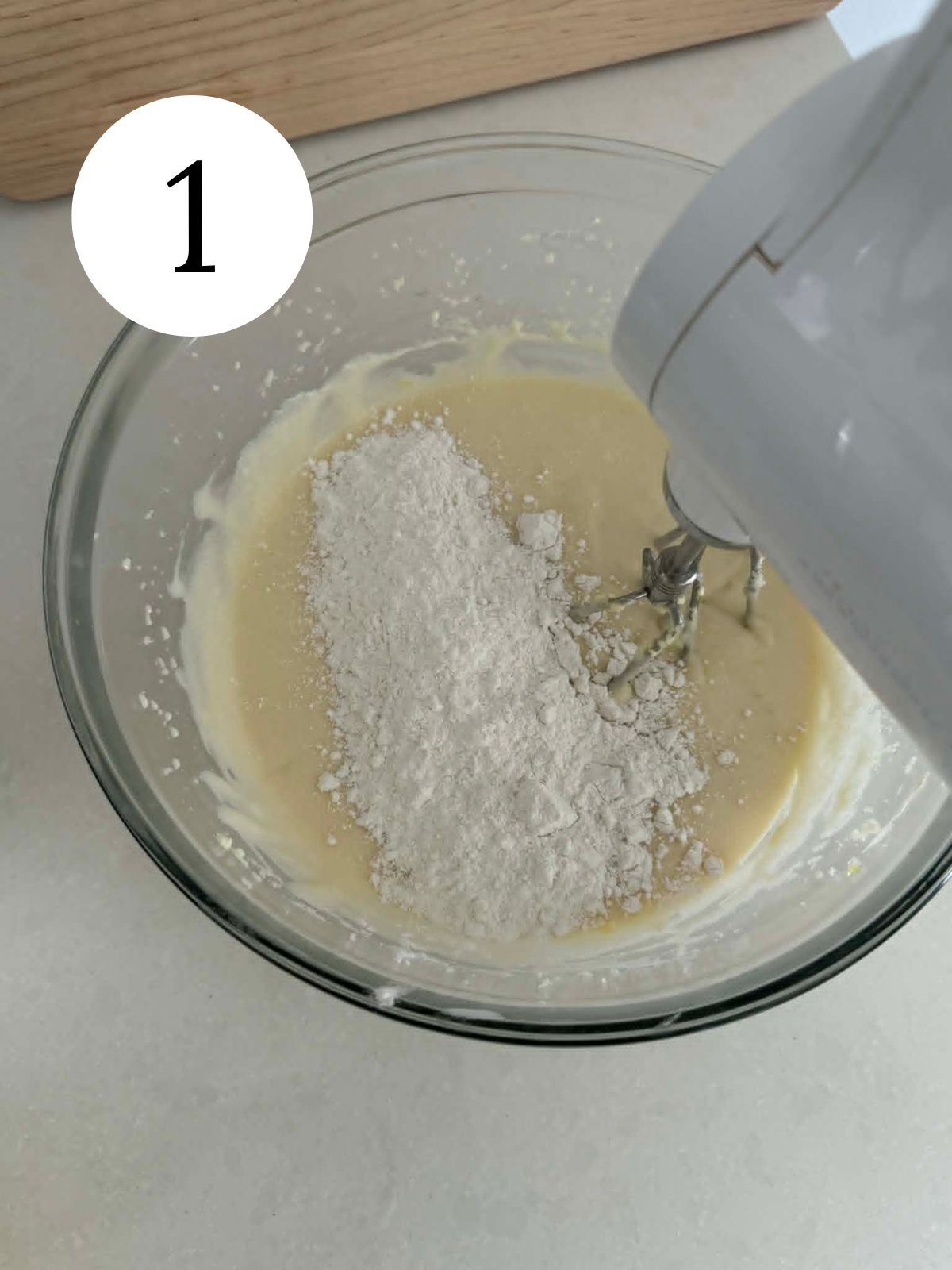 Dry ingredients on top of batter in a bowl with a mixer.