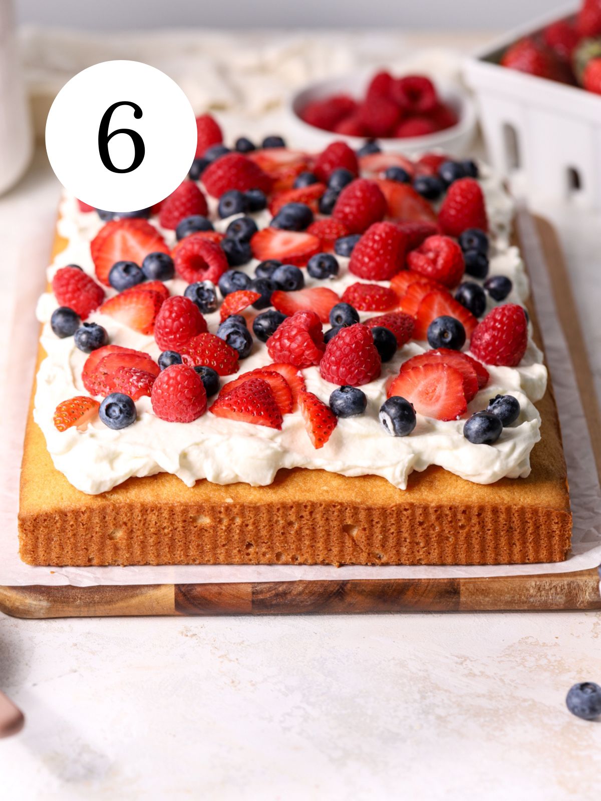 A sheet cake topped with whipped cream and fresh berries.