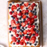 A sheet cake with whipped cream and berries on top.