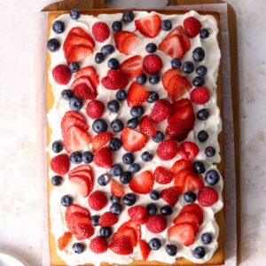 A sheet cake with whipped cream and berries on top.