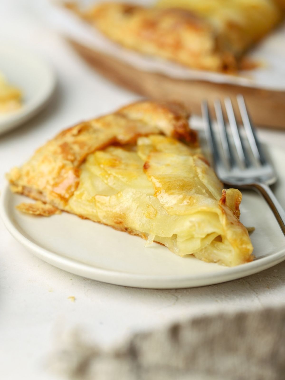 A slice of apple tart on a plate with a fork.