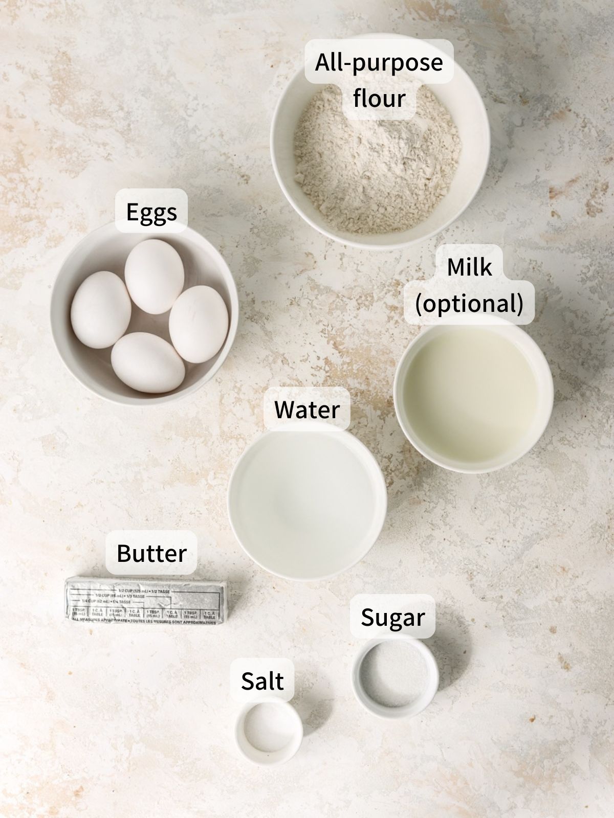 Labeled ingredients needed to make choux pastry laid out on a table.