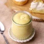 A jar of pastry cream and some cream puffs with pastry cream and whipped cream.
