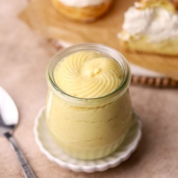 A jar of pastry cream and some cream puffs with pastry cream and whipped cream.